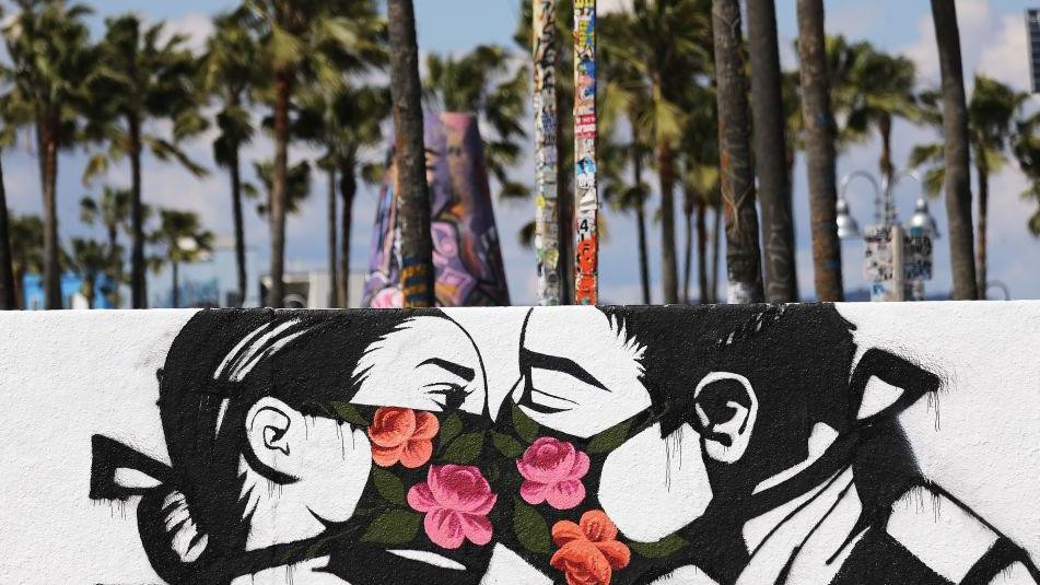 Ulična slika na kojoj se muškarac i devojka ljube sa maskama na licu