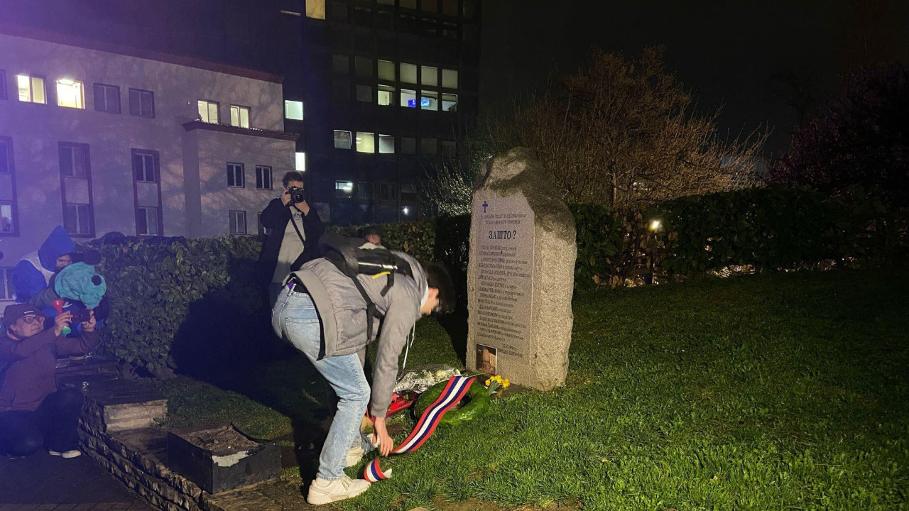Muškarac ostavlja venac pored spomenika tokom noći