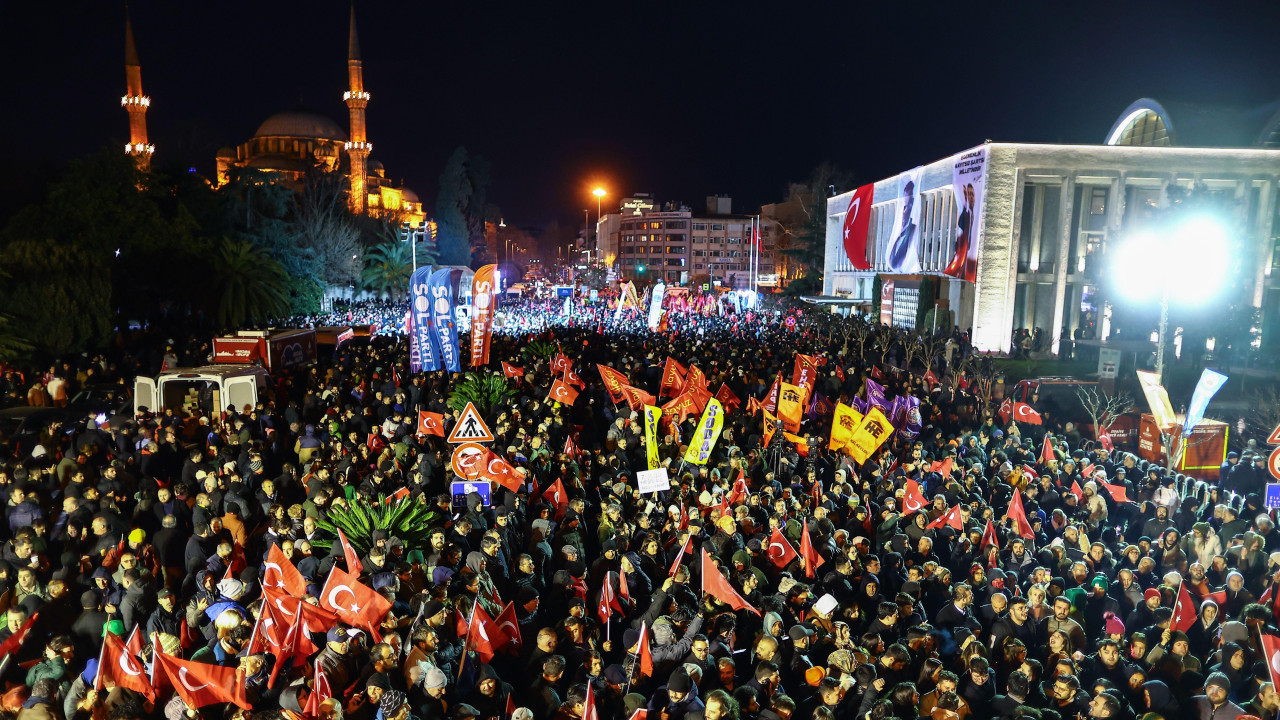 Crowds gathered at night waving flags outside Istanbul Municipality headquarters on 19 March 2025 