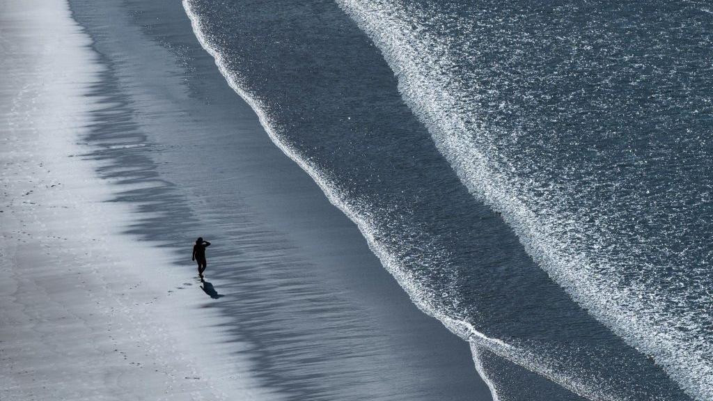 Čovek hoda sam na plaži