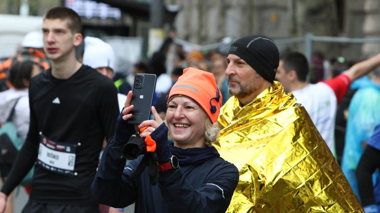 žena fotografiše dok je iza nje muškarac sa pokrivačem
