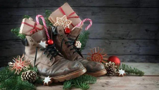 Dve čizmice u kojima su pokloni, a oko kojih su novogodišnji ukrasi