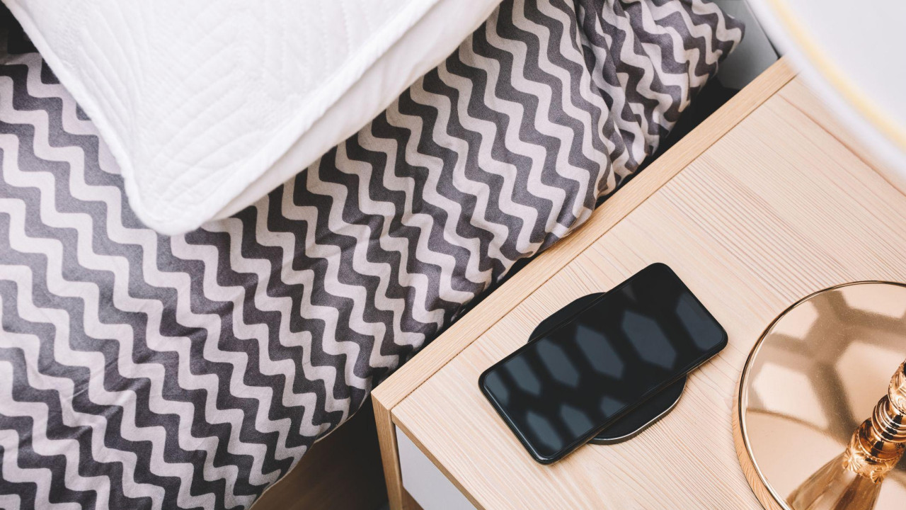 mobilni telefon na stočiću pored kreveta