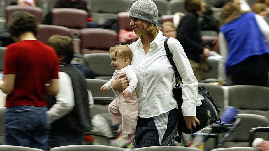 žena u naručju nosi bebu, hoda između sedišta u bioskopu 