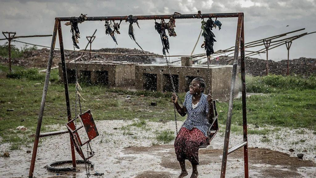 devojka sedi na ljuljašsci po pljusku i smeje se