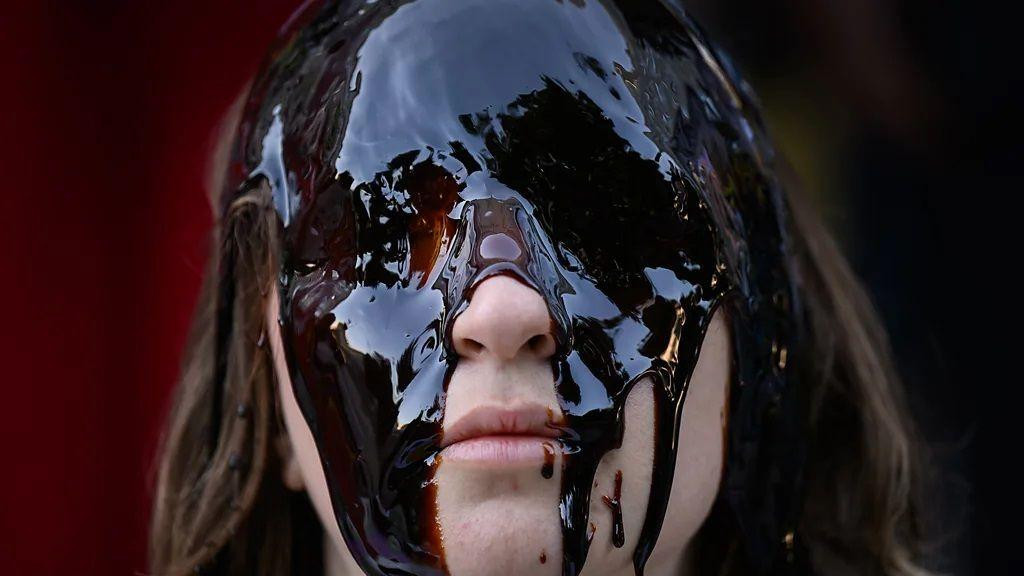 devojka stoji a oči su joj premazane tamnim uljem, protest zbog nafte, ekološki protest