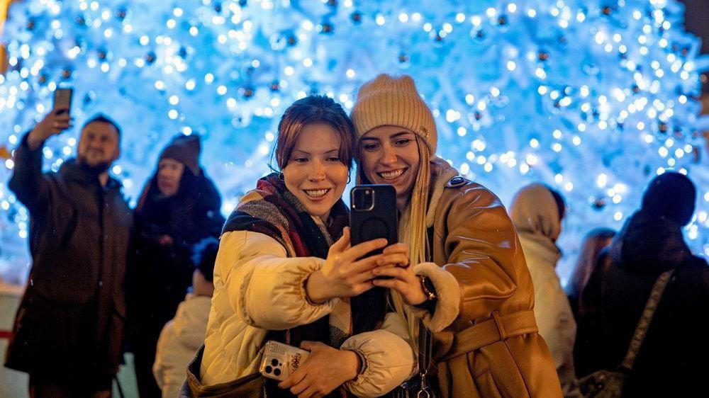 božić, proslava božića, dve devojke se slikaju ispred novogodišnjih ukrasa