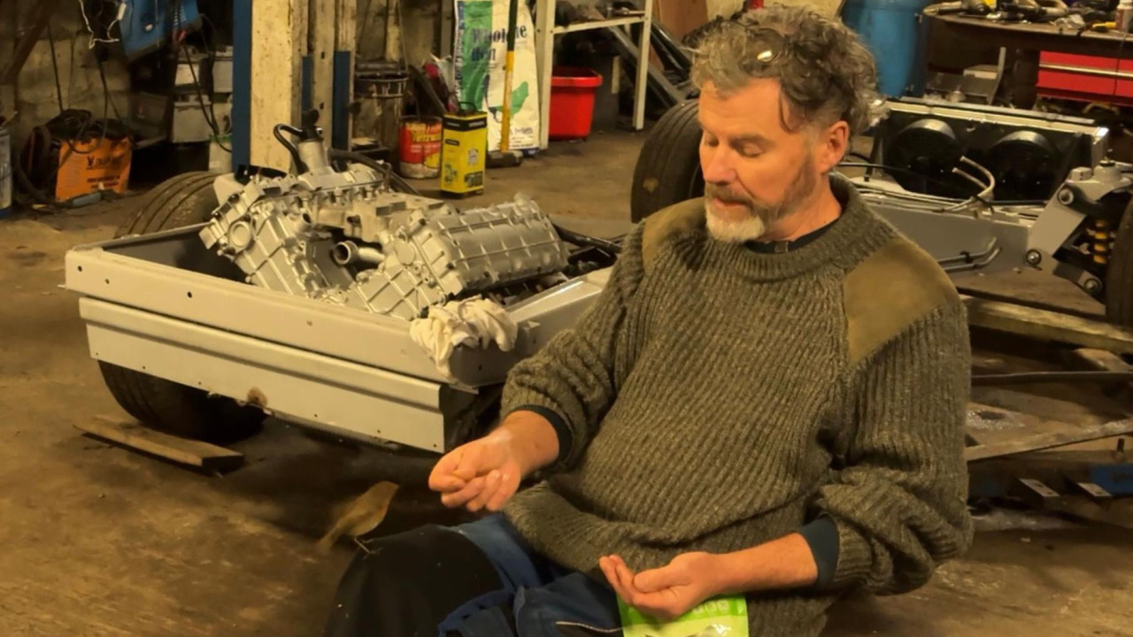 Muškarac iz kesice hrani crvendaća koji mu je na kolenu 