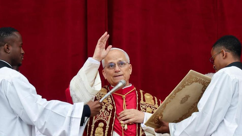 Pope Leo speaking into a microphone during his Christmas address and holding his hand in the air