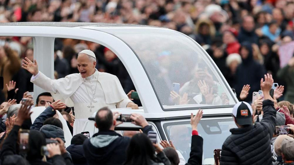 The Pope waves to worshippers from the popemobile