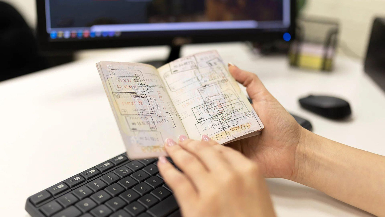 Žena drži otvoreni pasoš na čijim stranicama su različiti pečati