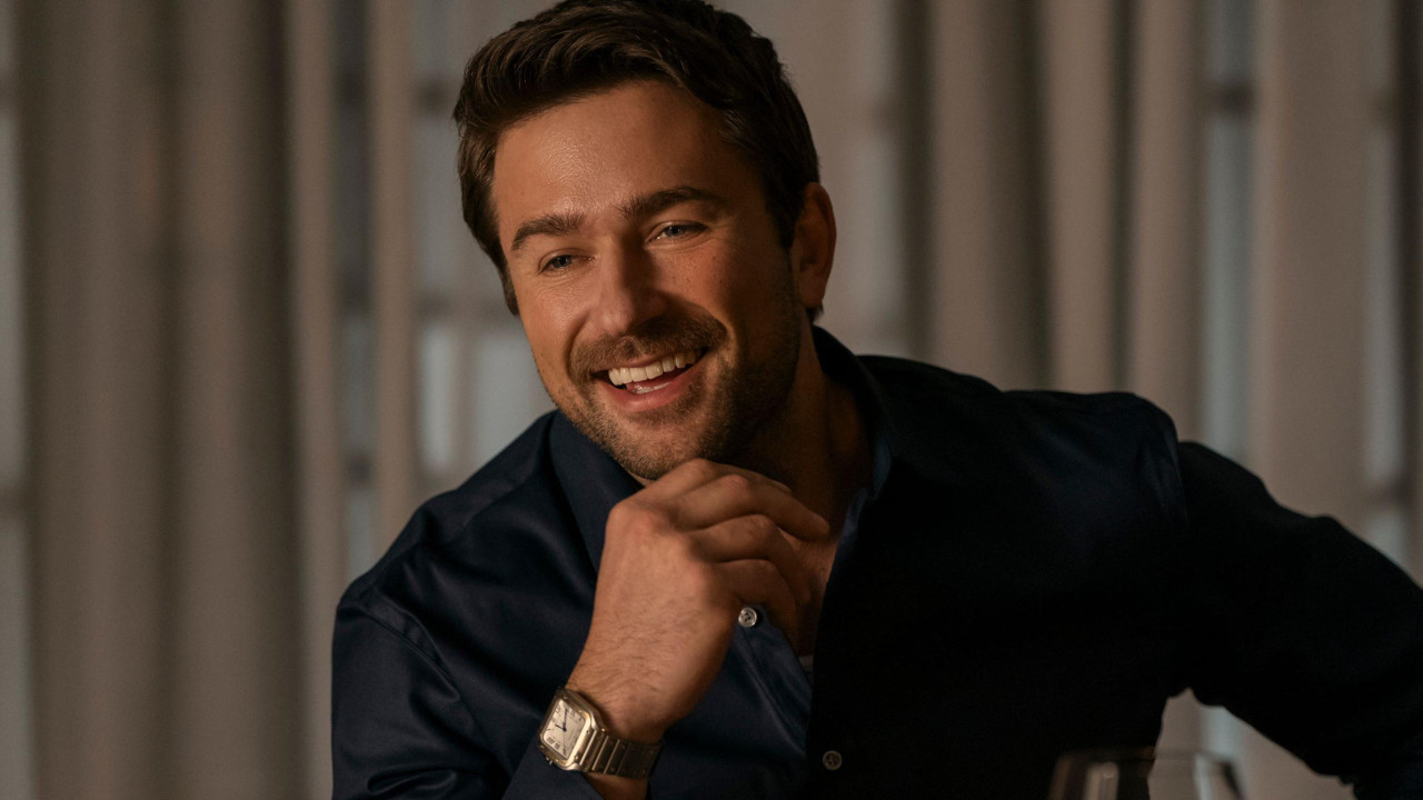 Glumac Brendon Sklenar pojavljuje se u filmu „Kućna pomoćnica“. Na slici se smeši dok podupire bradu rukom. Nosi plavu košulju.