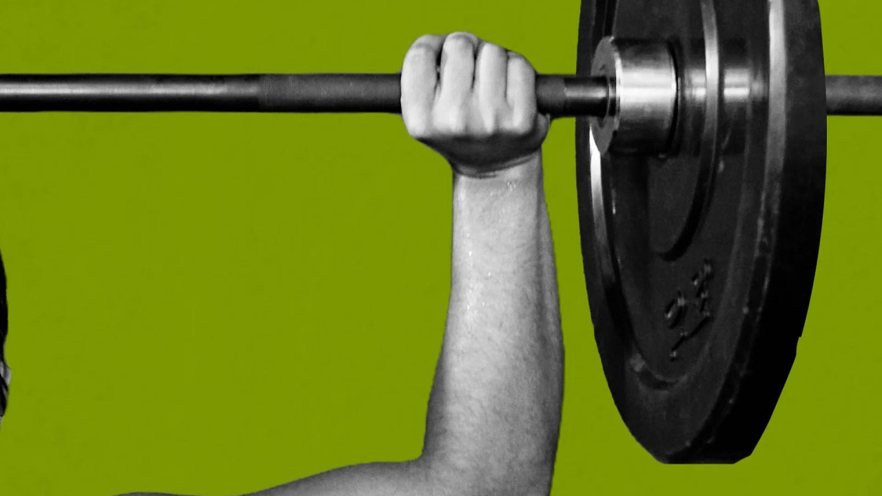 ruka koja podiže teg na zelenoj pozadini 