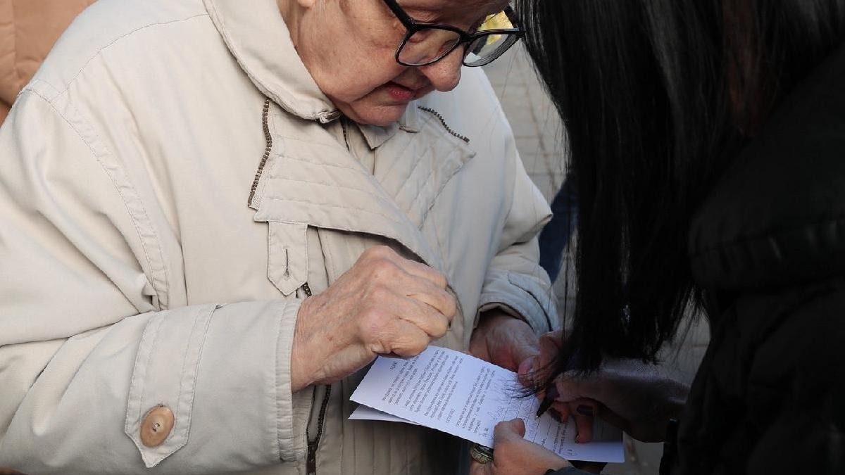 žena u bež kaputu potpisuje 