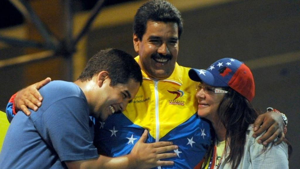 Maduro grli svog sina - takođe Nikolasa - i suprugu, Siliju. Silija se osmehuje Nikolasu mlađem, koji tapše oca po grudima. Maduro stariji ima širok osmeh.