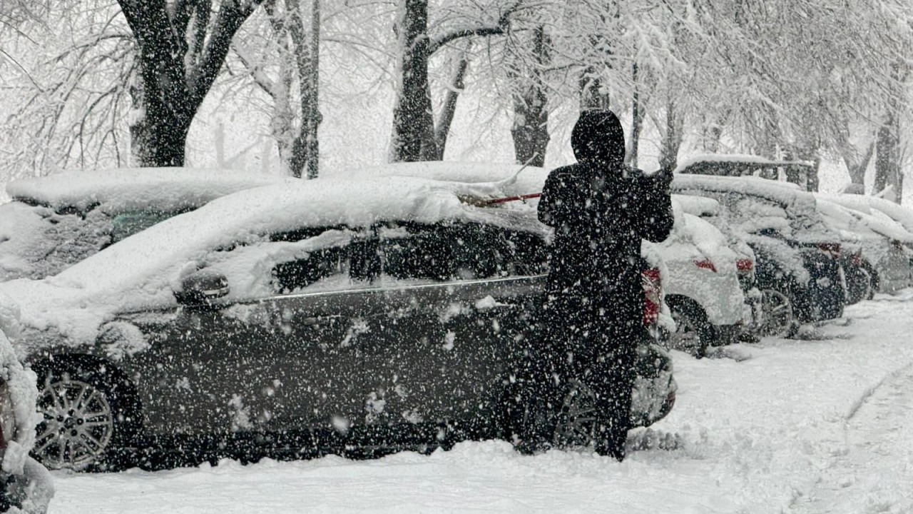 Čovek stoji pored automobila dok pada sneg u Sarajevu