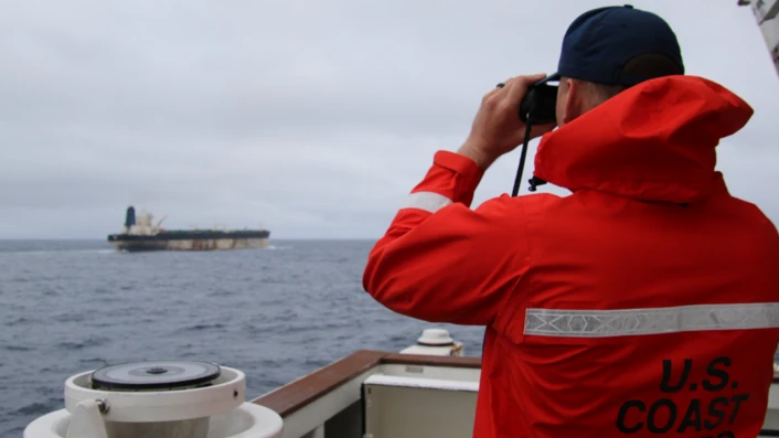 Muškarac sa dvogledom nadgleda more i brodove