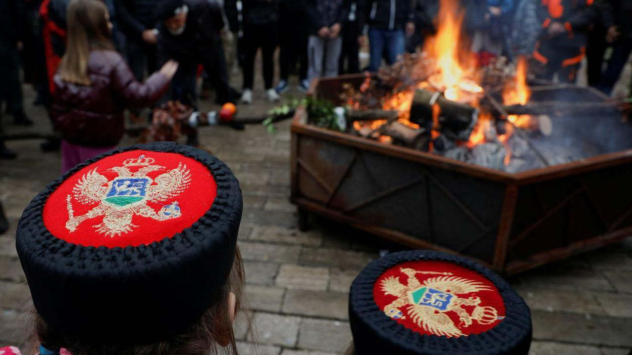 Kape sa tradicionalnim simbolima Crne Gore u daljini gori badnjak