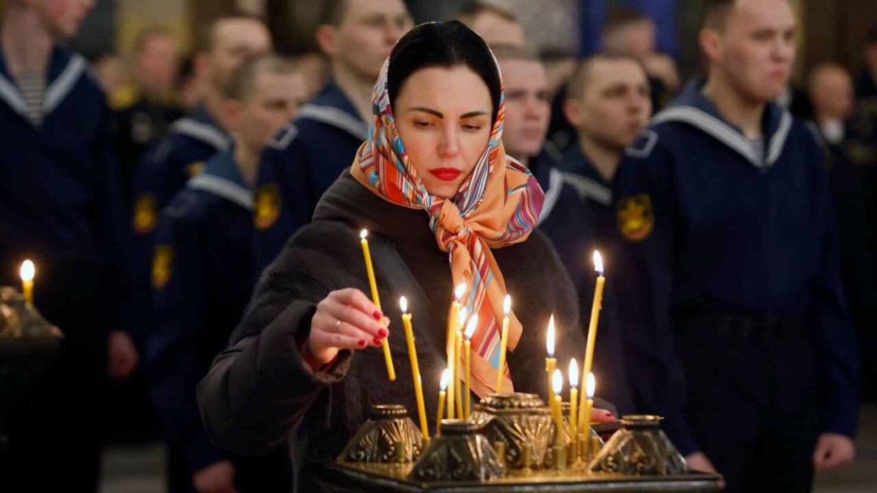 Devojka sa maramom na glavi pali sveću