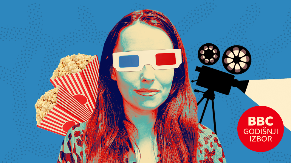 Devojka sa 3D naočarima iza koje su dve kutije pune kokice i kamera sa filsmkom trakom