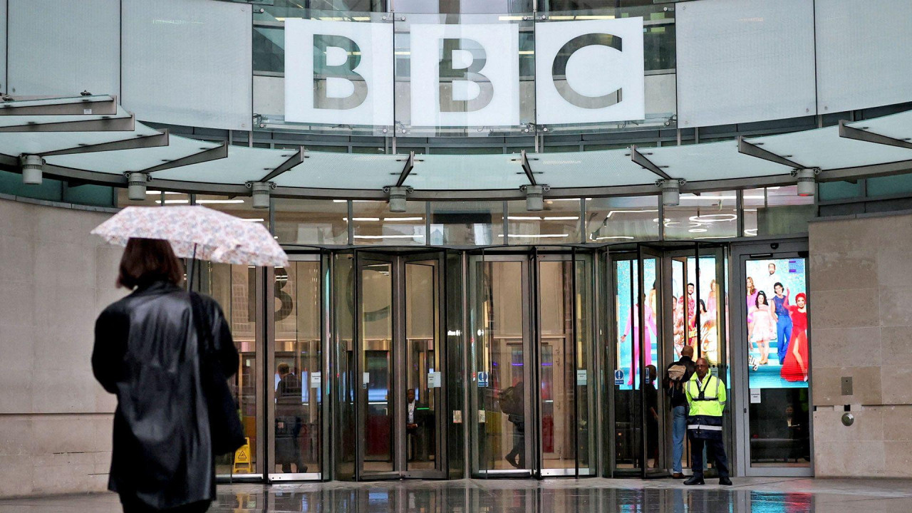 A person walks with an umbrella outside BBC Broadcasting House in London in November 2025