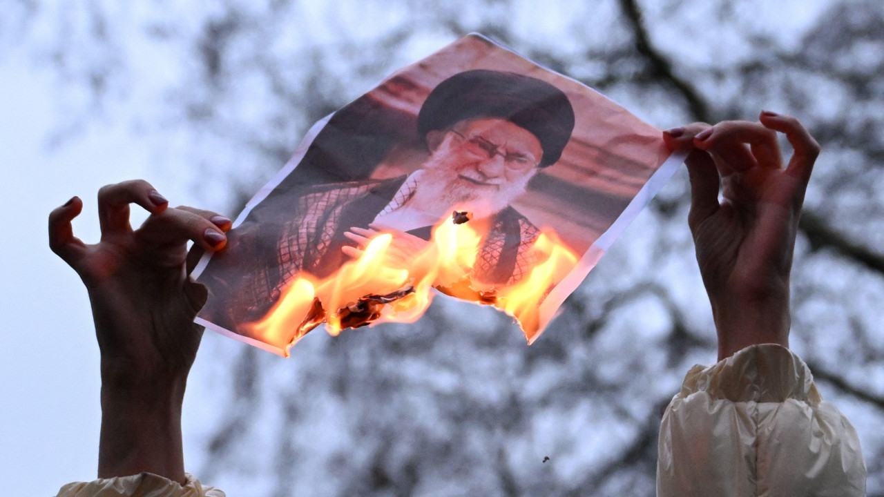 Demonstrantkinja u Londonu, na skupu podrške protestima u Iranu, drži zapaljenu sliku ajatolaha Hamneija 