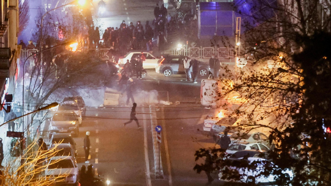 protesti u iranu, iran, demonstranti u Iranu oko parkiranih automobila na ulici. Vidi se dim, a u blizini gori vatra