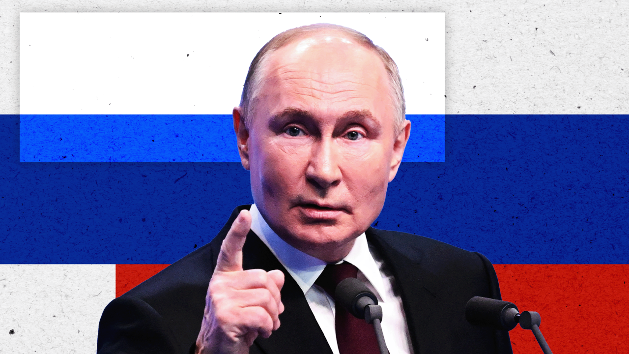 Vladimir Putin pokazuje prstom, a iza njega je pozadina sa elementima ruske zastave