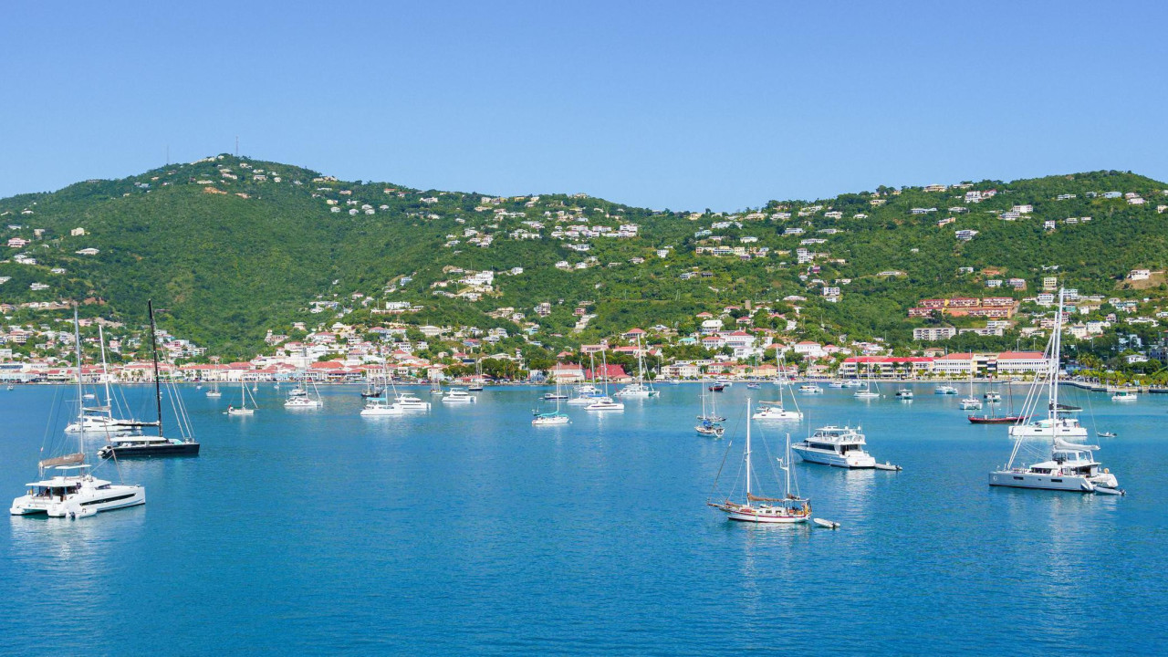 
                    Beli čamci usidreni u zalivu plave vode, ispred zelenih, drvećem obraslih brda isprekidanih belim zgradama, na ostrvu Sent Tomas na Američkim Devičanskim Ostrvima.
     