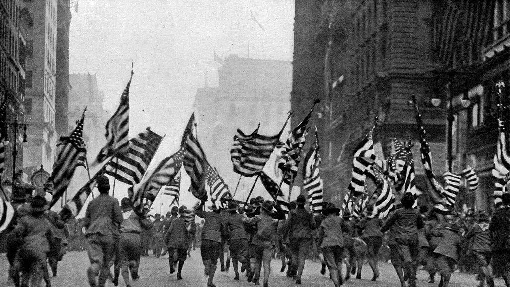Ljudi trče niz ulicu u Njujorku, mašući zastavama SAD, na demonstracijama izviđača odmah nakon objave rata, aprila 1917. godine, crno-bela slika iz 1917. godine.