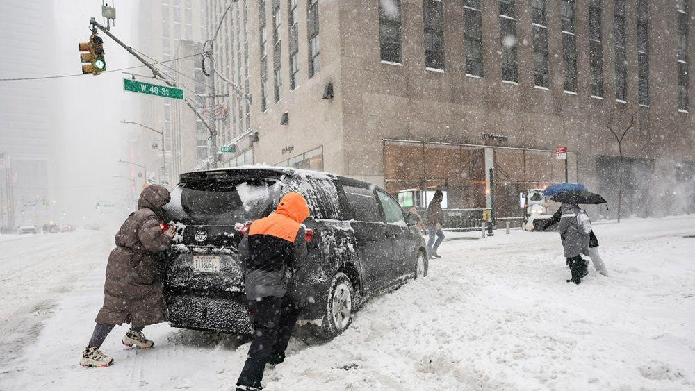 Ljudi pomažu da se pogura vozilo blizu Tajms skvera dok se velika zimska oluja širi velikim delom Sjedinjenih Država