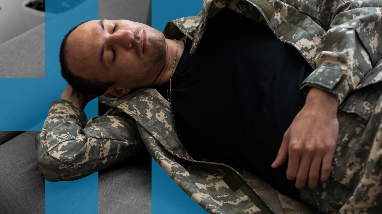 Vojnik u kamuflažnoj jakni i pantalonama leži a ruka mu drži glavu na krevetu. Oči su mu zatvorene, kao da spava, ili kao da će uskoro zaspati.