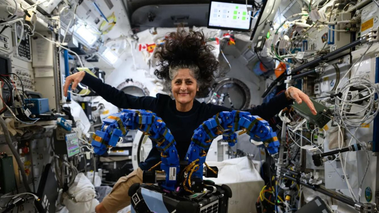 Astronautkinja Sunita Vilijams lebdi u svemirskom brodu, okružuju je ekrani i kablovi, ima dugu prosedu, tamnu kosu i nosi crnu majicu, smeška se u kameru