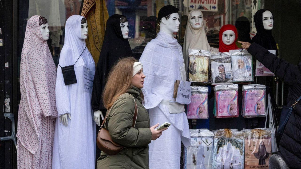 Žena prolazi pored prodavnice u kojoj se prodaje hidžab