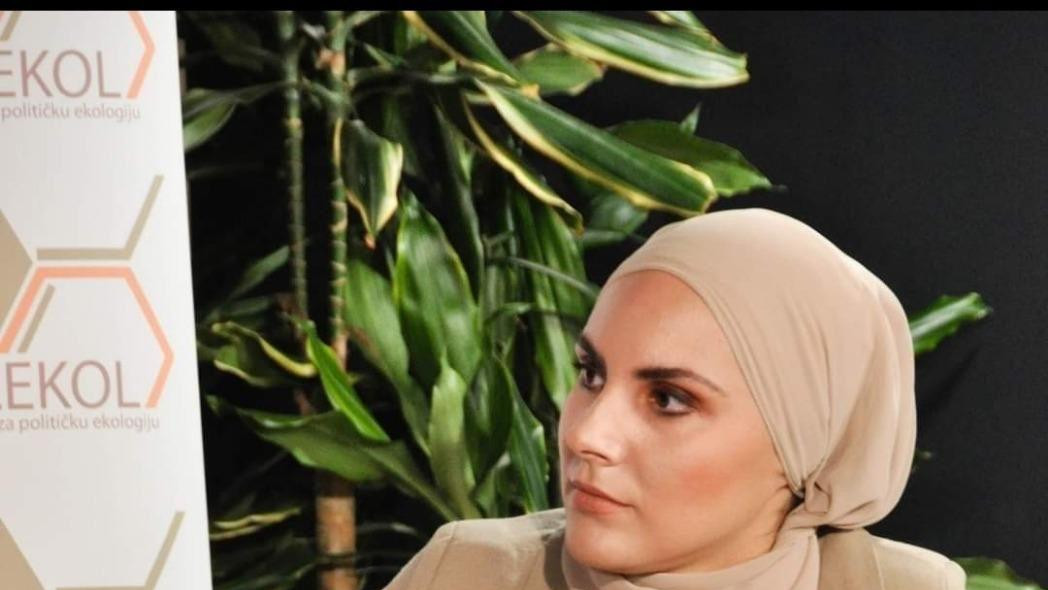 Devojka prekrivene glave sedi za govornicom