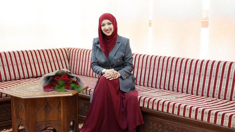 Žena sa maramom na glavi sedi na trosedu