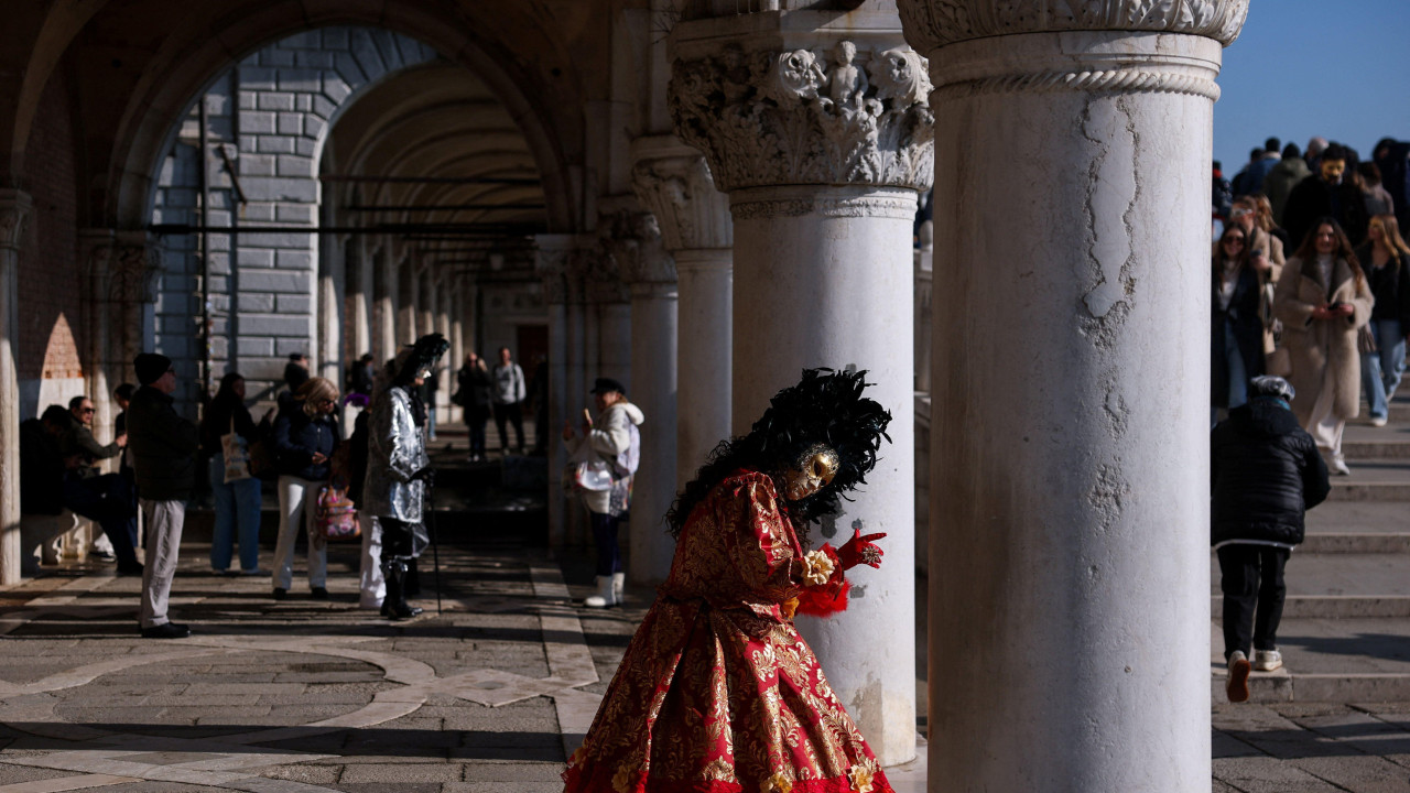 učesnica karnevala u Veneciji stoji pored stuba na Trgu svetog Marka, prvog dana Venecijanskog karnevala 