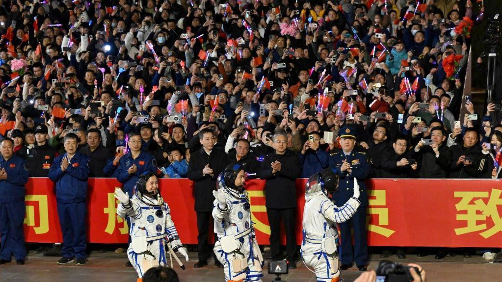 Tri kineska astronauta prolaze pored gomile ljudi koji mašu zastavama, kamerama i telefonima pred odlazak u svemir kako bi sproveli istraživanje na svemirskoj stanici Tjangong