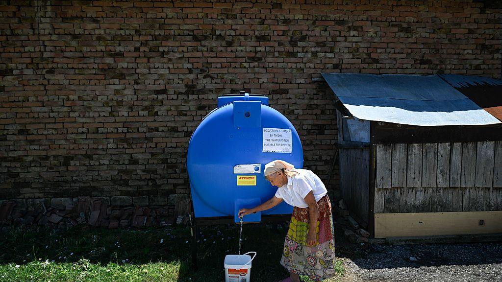 starija žena punu kofu vode sa cisterne u Bugarskoj 