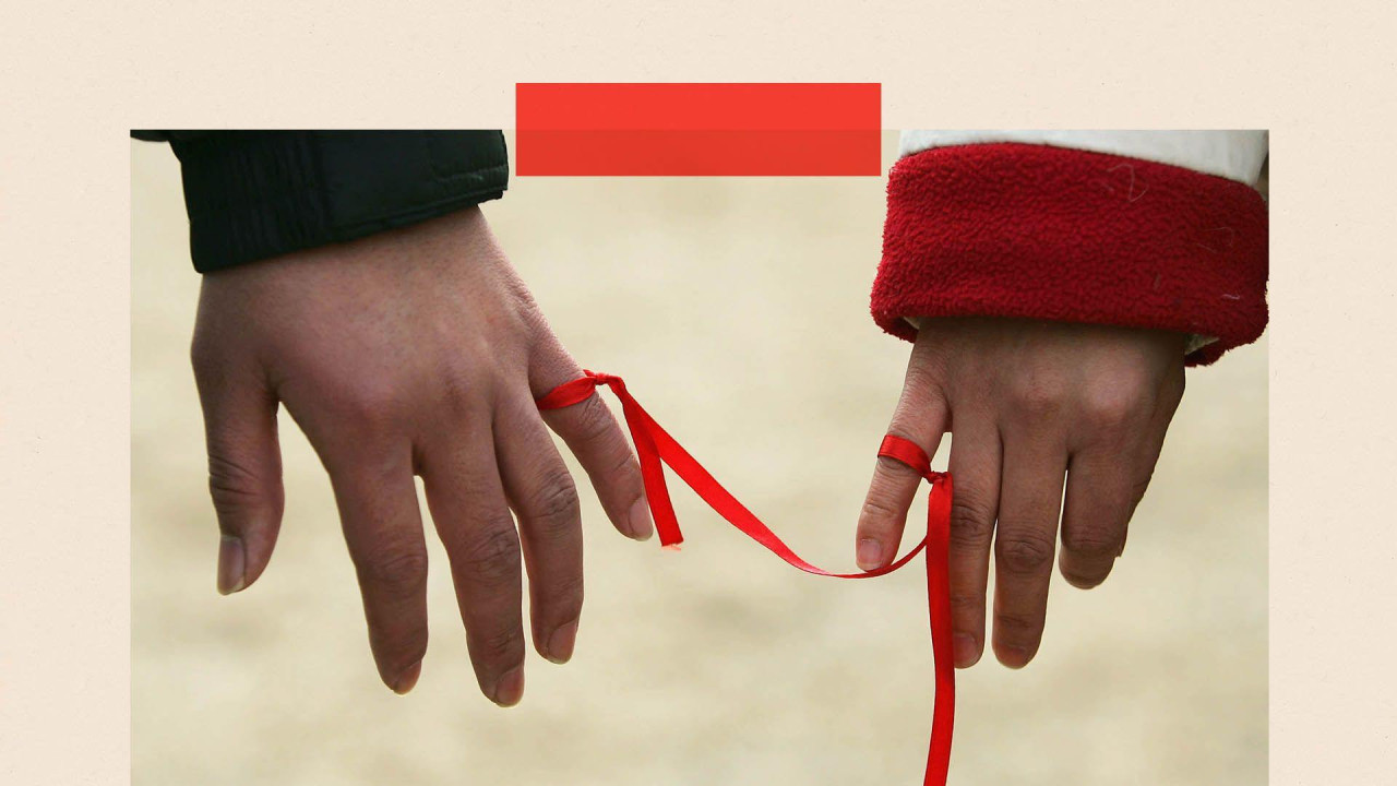 dvoje ljudi sa vezanom crvenom trakom oko malih prstiju 