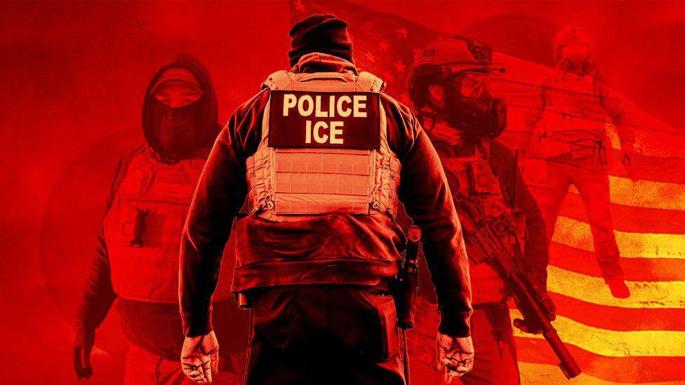 pripadnici službe ICE u americi, dvojica nose maske preko lica, u pozadini je američka zastava